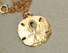 Gold sand dollar necklace - delicate necklace - a dainty gold sand dollar hanging from a 14k gold vermeil chain This delicate gold sand dollar is made of 14k gold vermeil and hangs from an 18 inch 14k gold vermeil chain. Please feel free to select a different length if you prefer... I can also make a set of matching dangling earrings if you like. Sand dollar measurement: 16mm Here is a set of super cute sand dollar stud earrings... https://www.etsy.com/listing/151300907/sand-dollar-earrings-stud Gold Round Pendant Necklace For Beach, Gold Sterling Silver Jewelry For Beach, Delicate Gold Beach Jewelry, Delicate Gold Necklace For Beach, Gold 14k Gold Filled Necklaces For Beach, Beach Jewelry In 14k Gold Filled, Gold Sterling Silver Necklace For Beach, Gold Round Pendant Jewelry For The Beach, Sand Dollar Earrings