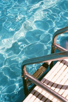 an empty chair sitting in the middle of a swimming pool with clear blue water behind it