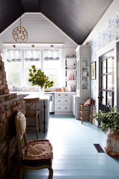 a kitchen with blue flooring and white cabinetry next to a brick fireplace in front of a window