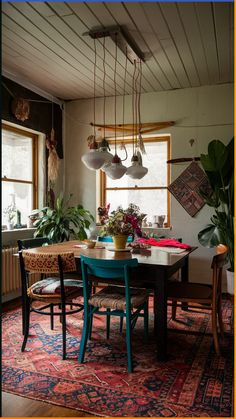 a dining room table and chairs with potted plants hanging from the ceiling