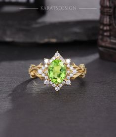 a ring with an oval cut green stone surrounded by small white diamonds on a black surface