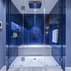 a blue tiled bathroom with glass shower doors