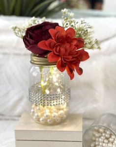 a vase filled with flowers sitting on top of a white box next to some pearls