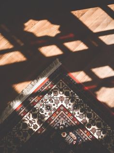 the shadow of a rug on top of a wooden floor with light coming through it