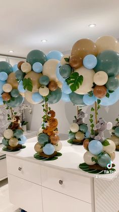 there are many balloons on the table with animals and plants in them, as well as other decorations