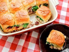 a casserole dish filled with sliders sitting on top of a red and white checkered table cloth