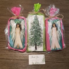 three christmas gift bags with angel images on them, one is wrapped in plastic and the other has a tag that says thank you