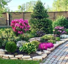 a garden filled with lots of flowers next to a wooden fence