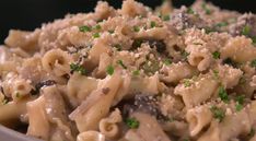 a bowl filled with pasta and meat covered in parmesan cheese, green garnish