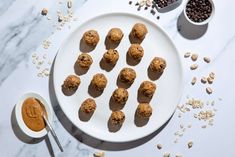 a white plate topped with cookies next to bowls of peanut butter and oatmeal