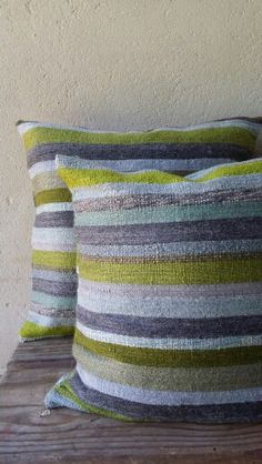 two striped pillows sitting on top of a wooden bench