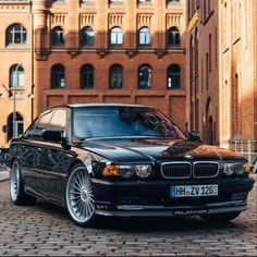 a black car parked in front of a tall building on a cobblestone street