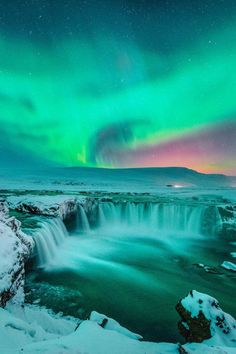 the aurora bore is seen over a frozen waterfall