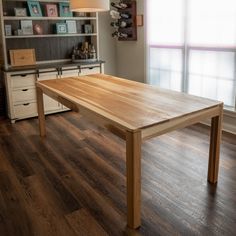 a wooden table sitting on top of a hard wood floor next to a book shelf