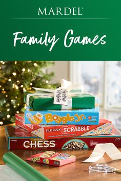 a pile of family games sitting on top of a table next to a christmas tree