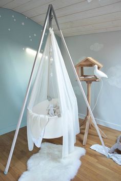 a baby's room with a hammock in the corner and other items on the floor