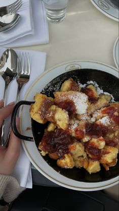 a pan filled with food sitting on top of a table next to utensils