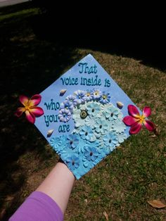 a hand holding a decorated cap with flowers on it