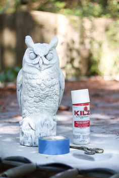 an owl statue sitting on top of a table next to a can of kleenex