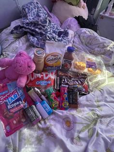 a teddy bear sitting on top of a bed covered in food and candy next to a stuffed animal