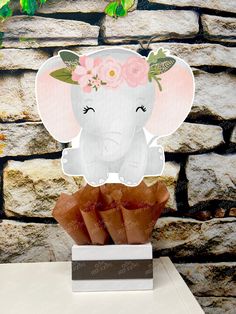 an elephant with flowers on it's head sitting in front of a stone wall