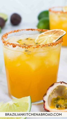 two glasses filled with orange and lime margarita cocktails on a white tablecloth next to an avocado