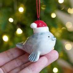 a small bird ornament with a santa hat on it's head hanging from a christmas tree