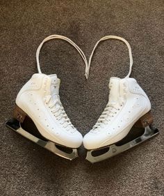 two white ice skates sitting on top of a carpet