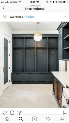 an empty laundry room with black cabinets and white counter tops, gold hooks on the wall