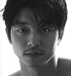 a black and white photo of a shirtless man looking at the camera with an intense look on his face