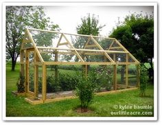 a small wooden greenhouse in the grass