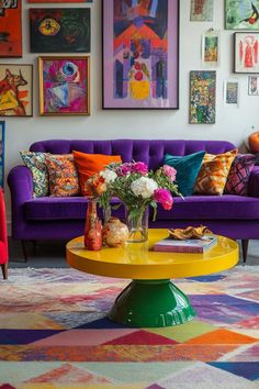 a living room with colorful couches and pictures on the wall above it, along with flowers in vases