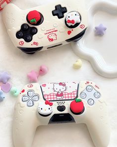 two video game controllers sitting next to each other on a white surface with hello kitty decorations