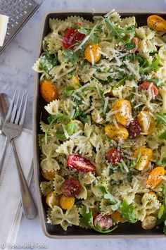 creamy pesto pasta with arugula and tomatoes in a casserole dish