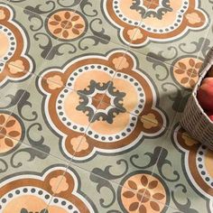 a basket filled with apples sitting on top of a floor next to a tiled floor