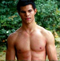 a shirtless young man standing in the woods