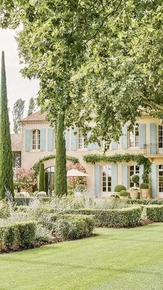 a large house with many trees and bushes in front of it, surrounded by lush green grass