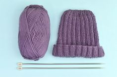 two knitting needles and a purple knitted hat