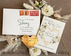 wedding stationery and envelopes with gold foil stamp on them, surrounded by dried flowers