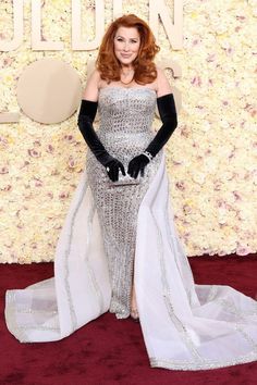 a woman in a silver gown and black gloves on the red carpet at an event