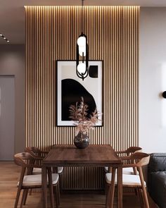 a dining room table with chairs and a painting on the wall behind it, in front of a couch