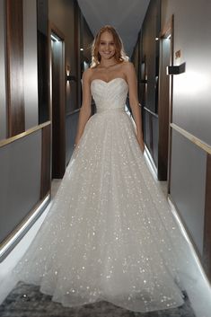 a woman in a wedding dress is walking down the hallway