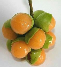 a bunch of fruit sitting on top of a white table next to a green leaf