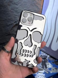 a person holding up a phone case with a skull on it