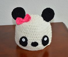 a crocheted panda bear hat with a pink bow on it's head