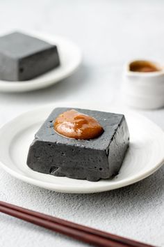 two plates with desserts on them and chopsticks next to one that has sauce in it