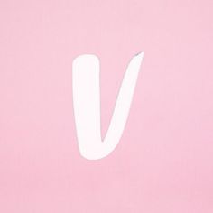 the letter v is cut in half and placed on a pink surface with white paint