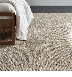 a bed sitting on top of a carpeted floor next to a wooden headboard