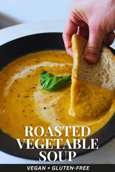 a hand dipping a tortilla chip into a bowl of roasted vegetable soup