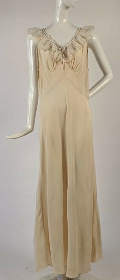 ANTIQUE 1930’S SOFTEST SILK LONG IVORY DRESS W RUFFLED NECKLINE  DATING TO THE 1930’S FASHIONED OF AN OFF WHITE IVORY SOFT SILK CREPE AND THERE ARE NO CLOSURES, MUST BE SLIPPED OVER THE HEAD TO BE WORN. THE V SHAPED NECKLINE IS TRIMMED IN MACHINE EMBROIDERED NYLON ORGANZA RUFFLES WITH A FLORAL PATTERN AND A SATIN RIBBON ENCIRCLING THE NECKLINE TO TIE CLOSED IN THE FRONT.   CONDITION:  TWO PINHEAD HOLES SEEN WHEN THE SKIRT IS HELD TO THE LIGHT WITH SIX VERY FAINT BROWN PINHEAD STAI Long Ivory Dress, Vintage Satin Dress, 1930s Fashion Women, Vintage 1930s Dress, Vintage Retro Clothing, Vintage Slip Dress, 1930s Dress, Ivory Dress, Vintage Slips